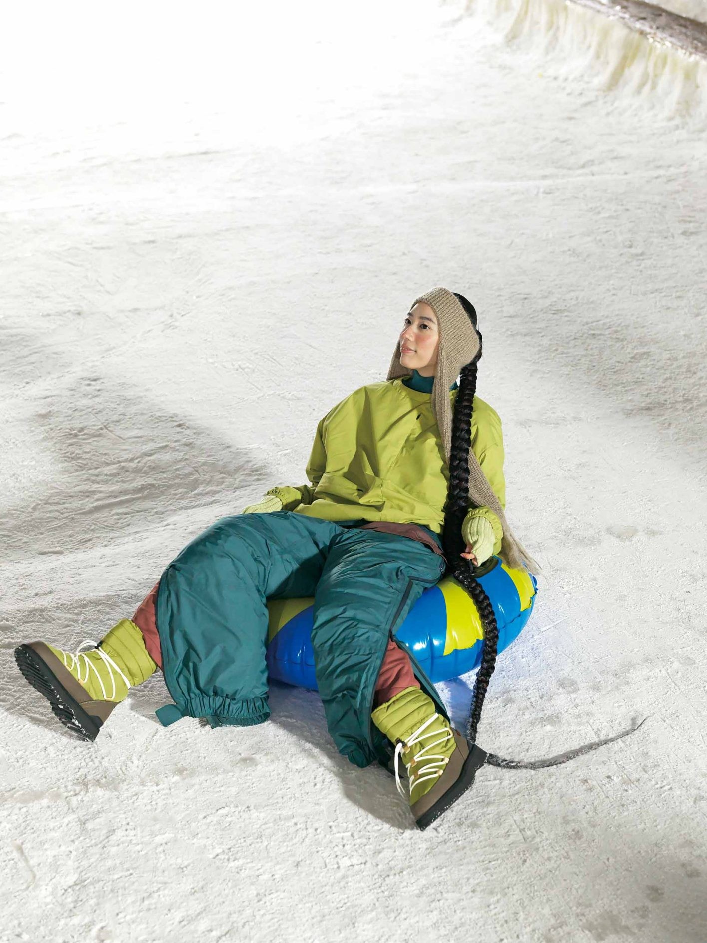 浮き輪みたいなポップなソリで滑る日は、グリーンを基調に茶色を効かせ、全身落ち着いたアーストーンに。上はアウトドアに最適な吸水速乾に優れたプルオーバーを加えた3枚重ね。極寒地でも頼れるダウンパンツの下に、中綿入りのパンツを忍ばせれば、防寒対策もばっちり。両サイドのファスナーを開けて、ちらりと裾を覗かせて。トップ ¥28,600、中に着たタートルネック ¥20,900、中に着たカットソー ¥12,100、パンツ ¥88,000、中に着たパンツ ¥24,2 00（以上スノーピーク）／ヘッドアクセ ¥ 34,000、アームウォーマー ¥18,000（共にキジマ タカユキ | サカス ピーアール）／スノーシューズ ¥36,300（スイコック）