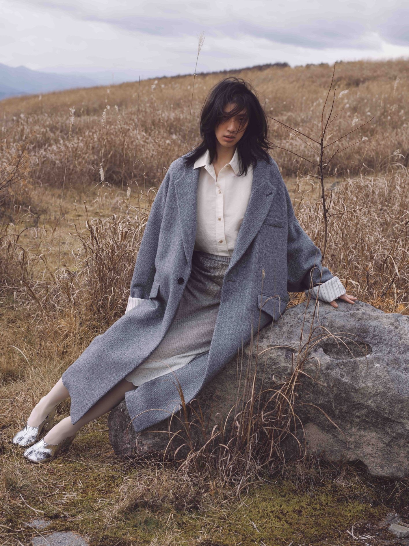 ふわりと身体を包み込むような丸いシルエットで仕立てられた、〈メゾン マルジェラ〉のウールコート。折り返した袖から現れる、ストライプの裏地もアクセント。「コートの袖幅が広いからか、どことなく打掛のような風情もありますね」(井伊さん)。コート ¥479,600、シャツ ¥209,000、スカート ¥229,900、シューズ ヒール8cm ¥209,000(以上メゾン マルジェラ | マルジェラ ジャパン クライアントサービス)/タイツ *スタイリスト私物